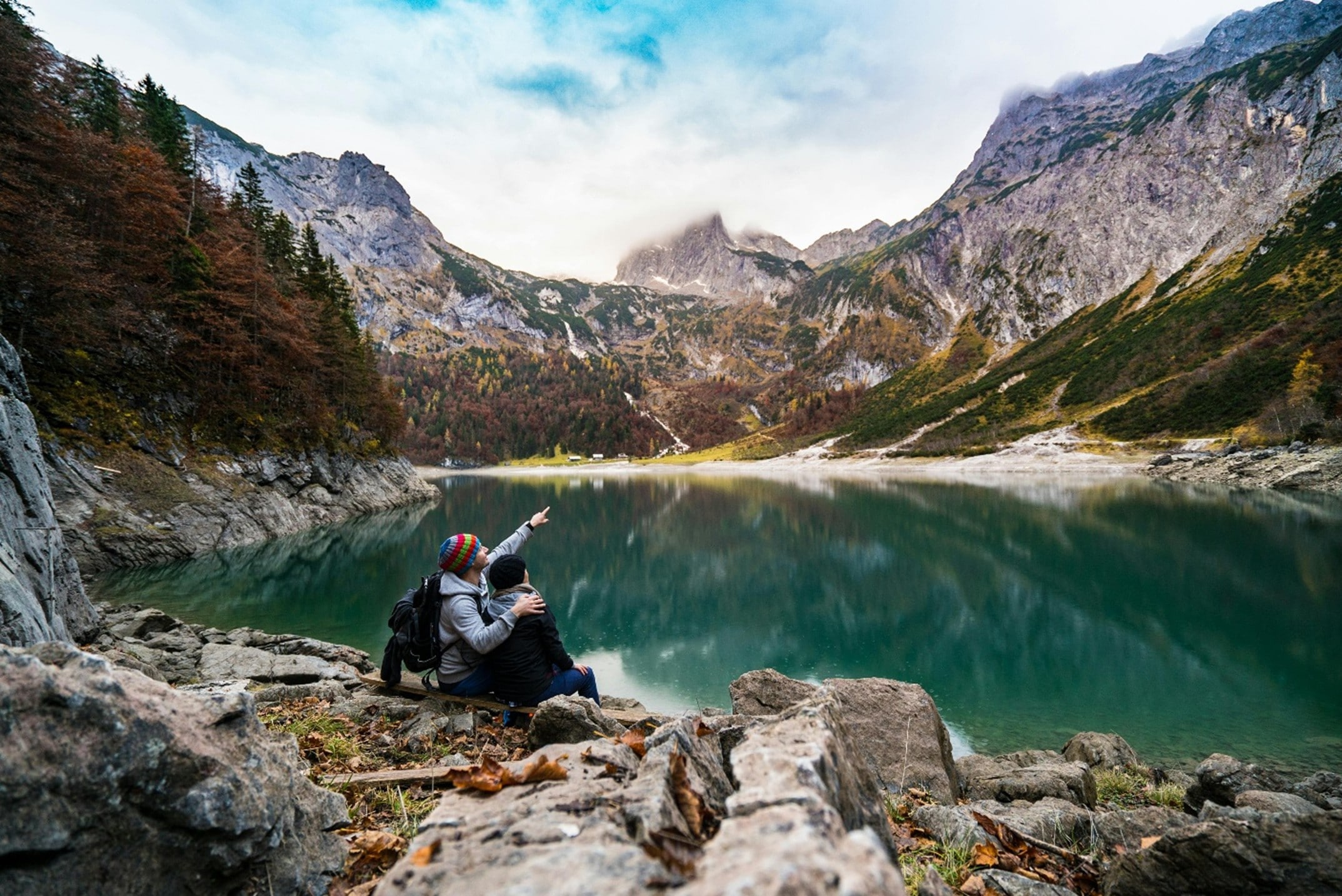 a couple sitting before a serene mountain landscape with a clear lake