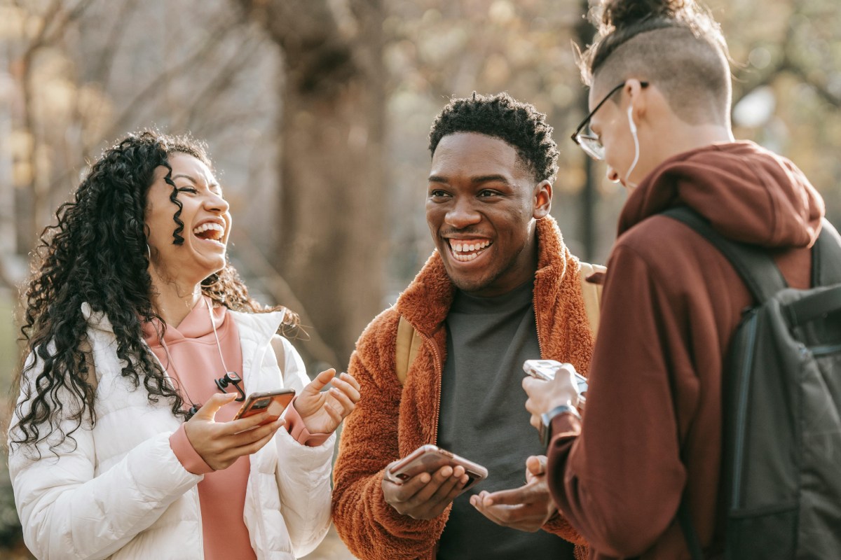 Group of three people laughing in a conversation